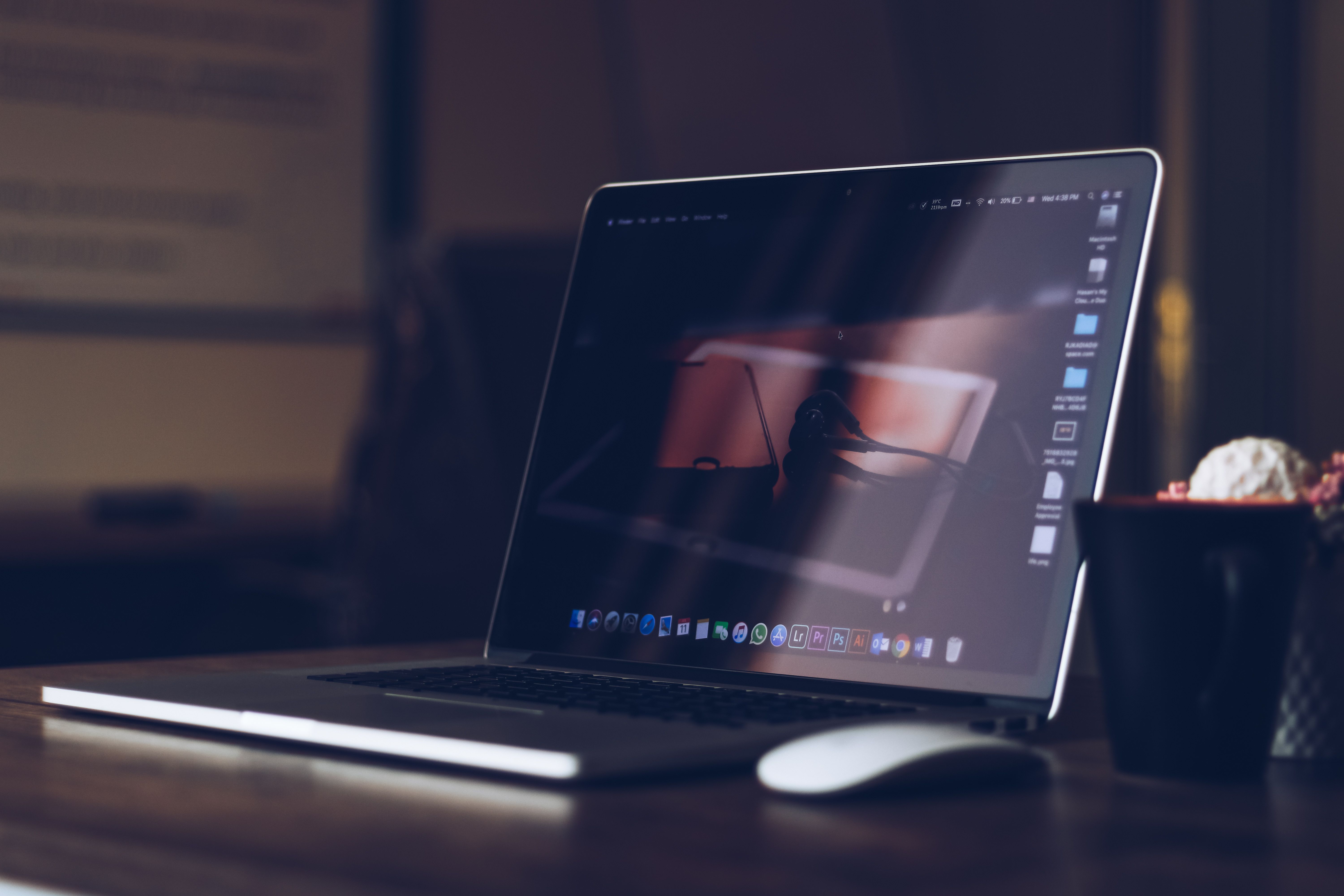 Laptop mit Designsoftware auf einem dunklen Schreibtisch