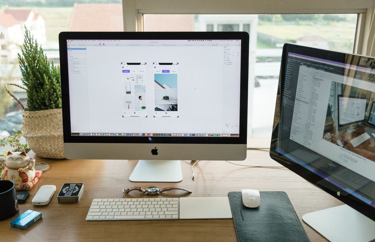 Kreativer Arbeitsplatz mit Monitor und Skizzen